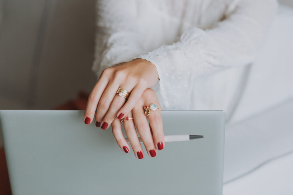 Mãos de mulher sobre o notebook segurando caneta lendo dicas para fechar negócio e assinar contrato